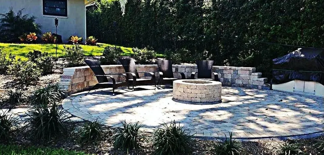 Round paver fire pit with seating and landscaping