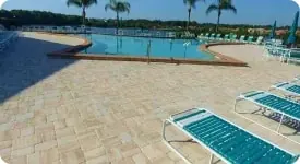 Large paver pool deck with loungers and a lake view