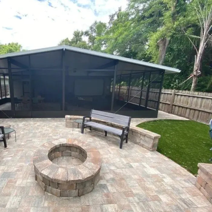 Paver patio with a round fire pit beside a pool screen enclosure
